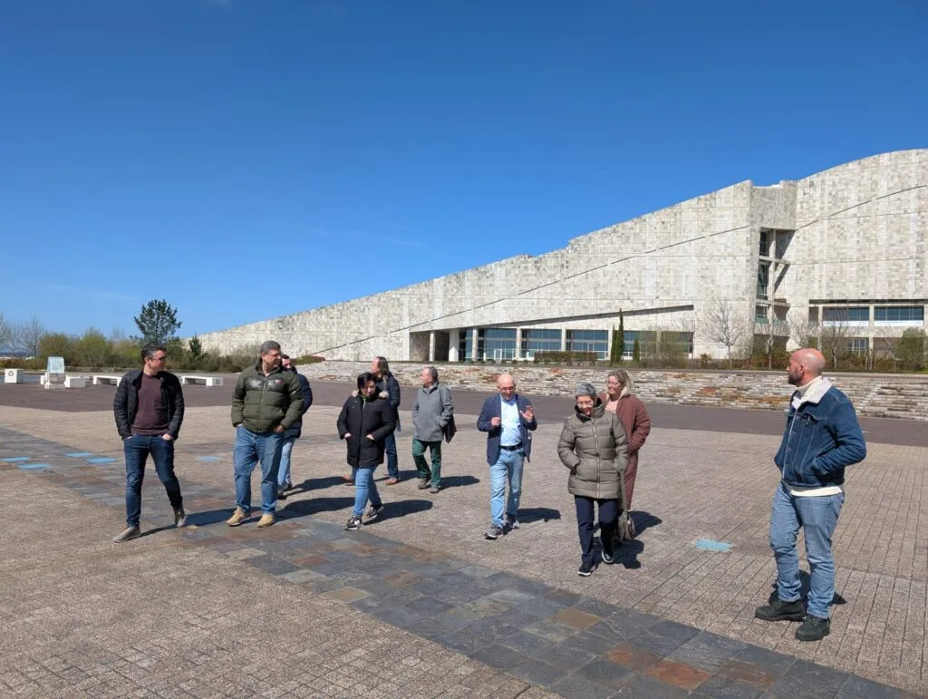 Grupo de visitantes camiña diante dos edificios da Cidade da Cultura de Galicia