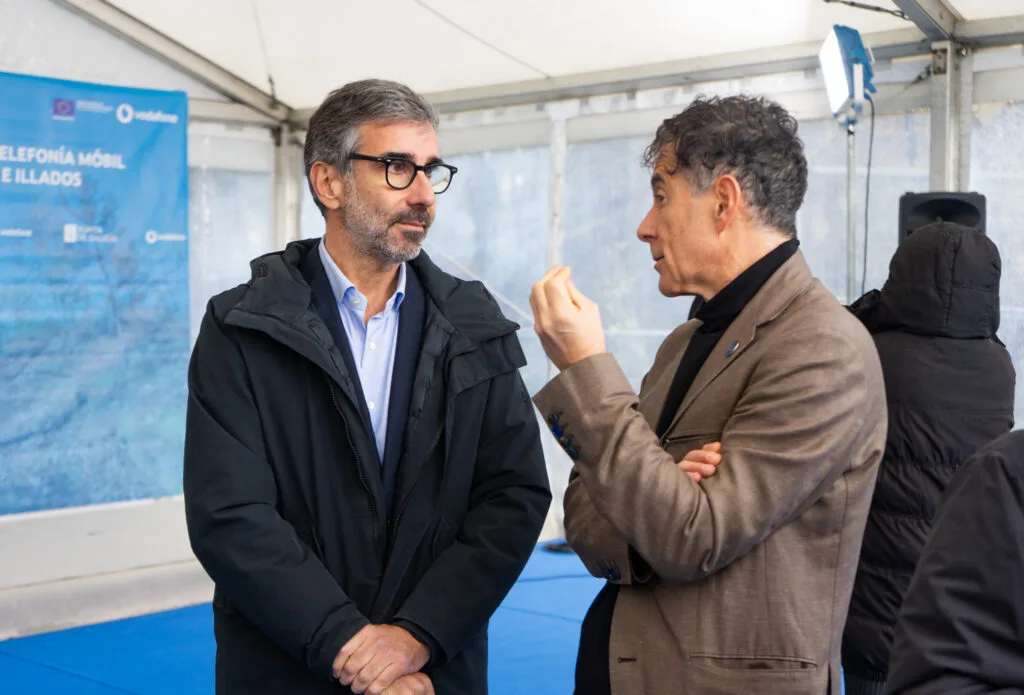 Dos asistentes conversan ante el panel del proyecto de extensión de la telefonía móvil en Leiro
