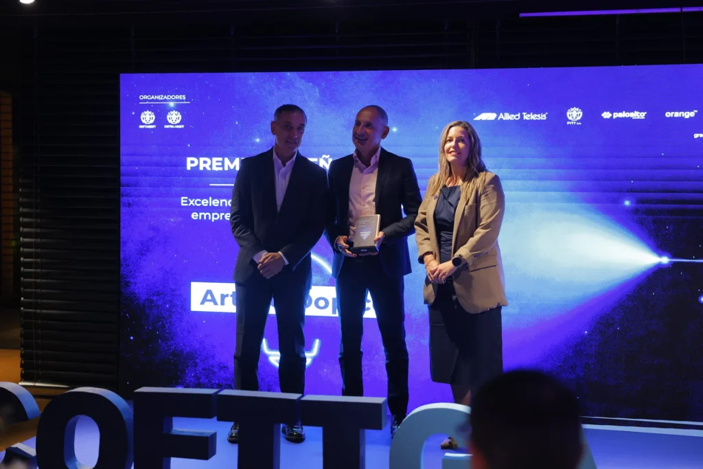Tres persoas posan sorrintes no escenario cun galardón dos Premios Enxeño